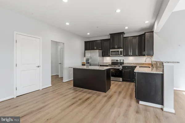 a kitchen with kitchen island granite countertop wooden floors and black cabinets