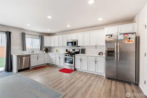 a kitchen with granite countertop a refrigerator oven a sink dishwasher and cabinets with wooden floor