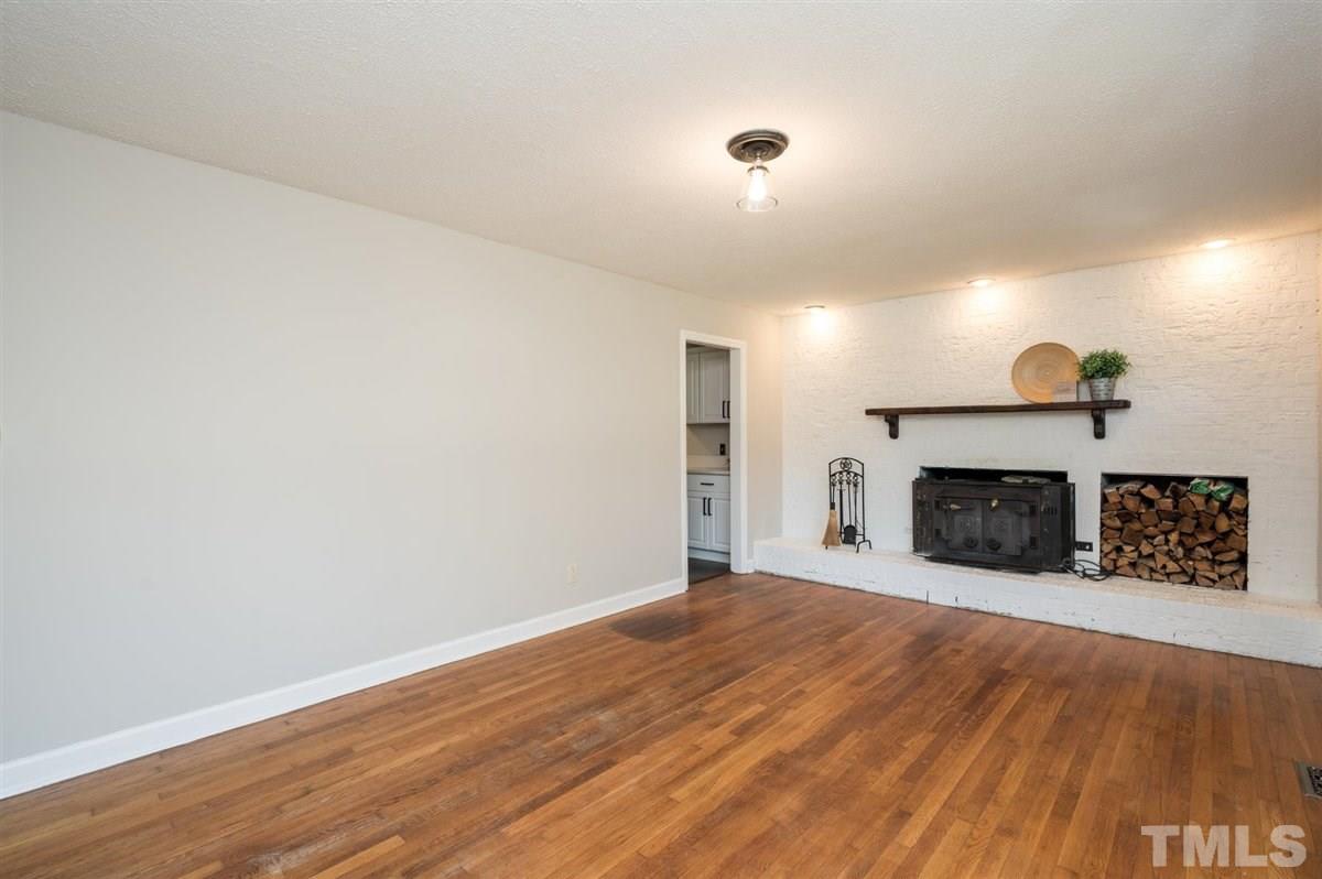 3814 Woodside Road Garner, NC 27529 - Photo 8 of 28 an empty room with wooden floor fireplace and windows