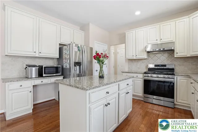 a kitchen with kitchen island granite countertop a sink cabinets and stainless steel appliances