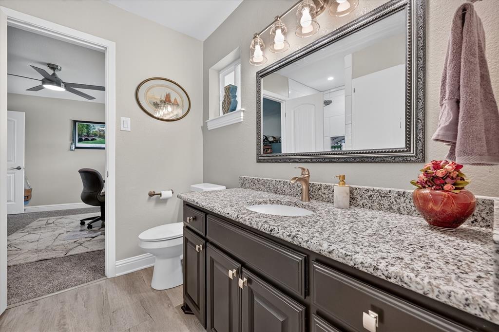 47 Bounty Road East Benbrook, TX 76132 - Photo 26 of 39 Bathroom vanity featuring a speckled countertop, dark wood-finish cabinetry, and a rectangular framed mirror with overhead vanity lighting