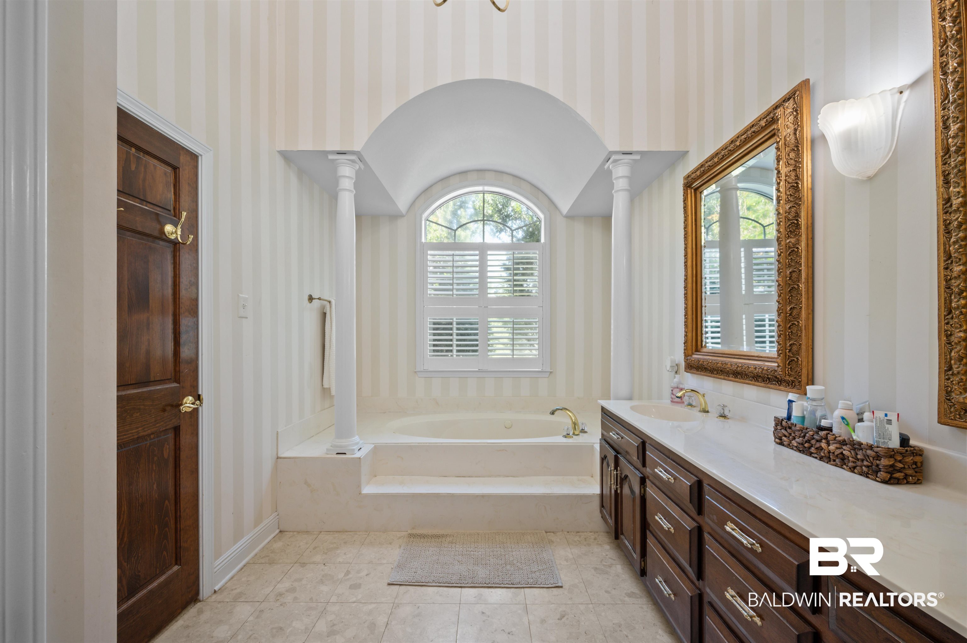 141 Blue Ridge Drive Monroeville, AL 36460 - Photo 25 of 40 Bathroom with decorative columns, wallpapered walls, vanity, a garden tub, and tile patterned floors