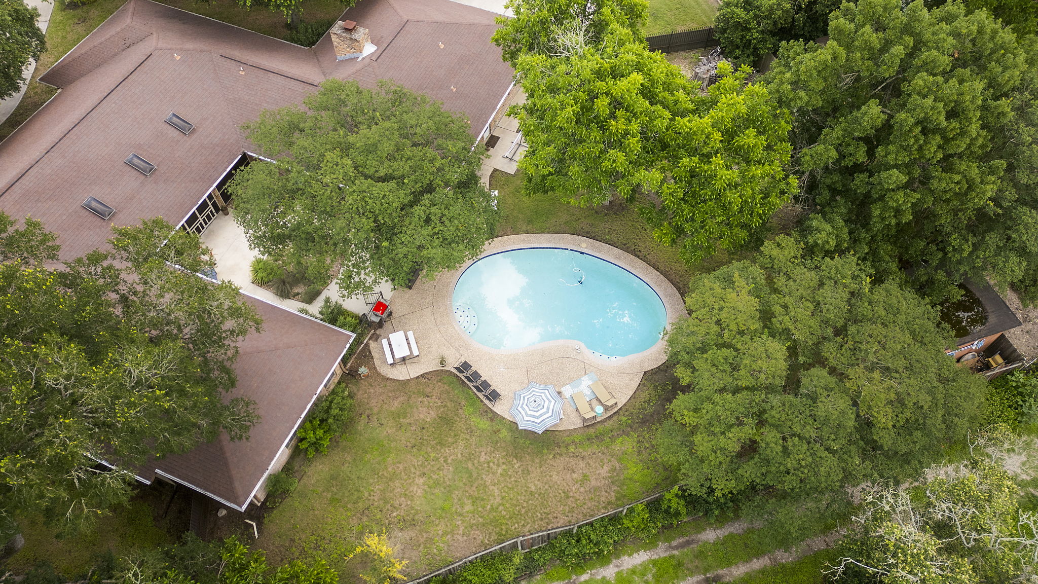 400 Hackberry Street Lockhart, TX 78644 - Photo 34 of 40 An aerial perspective reveals a private pool area amidst verdant trees and a spacious backyard.