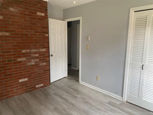 a view of an empty room with closet and wooden floor