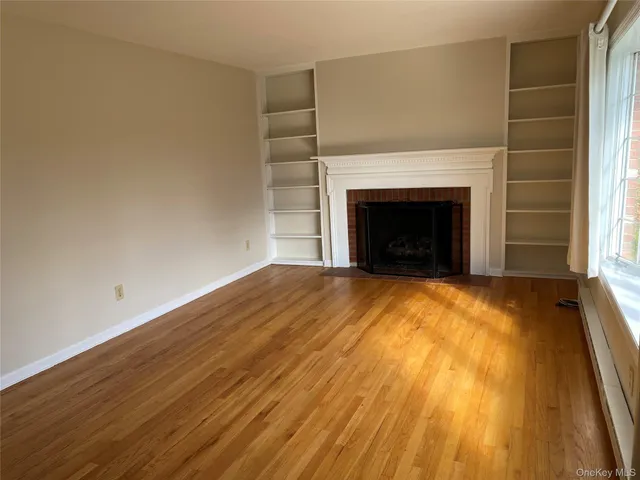 a view of empty room with wooden floor and fireplace