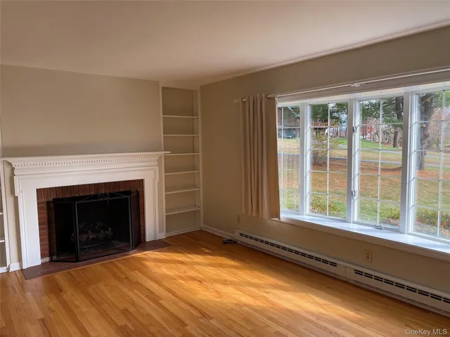 a view of an empty room with a fireplace and a window