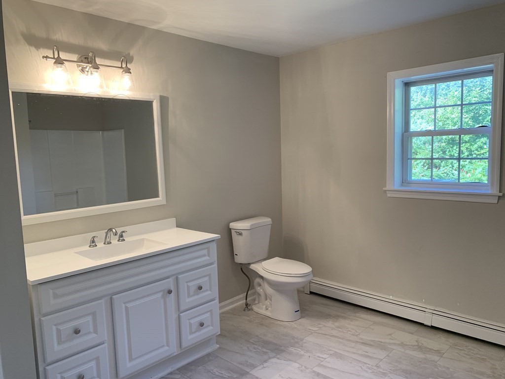 581 Warren Wright Road Belchertown, MA 01007 - Photo 13 of 25 a bathroom with a toilet sink a mirror and window