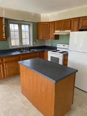 a kitchen with granite countertop a sink a counter top space and appliances