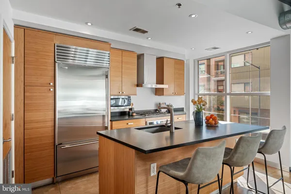 a kitchen with granite countertop a refrigerator a stove a dining table and chairs