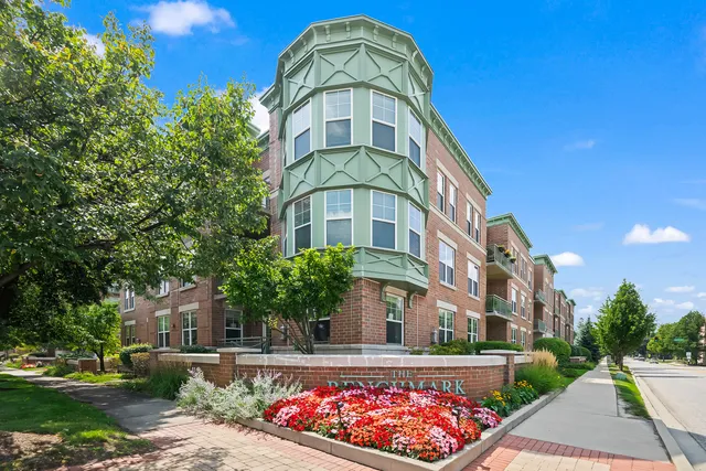 a front view of a multi story residential apartment building with yard and parking space