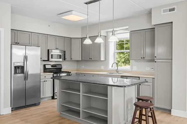 a kitchen with kitchen island granite countertop a sink cabinets stainless steel appliances and a window