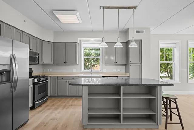 a kitchen with stainless steel appliances granite countertop a sink a stove a refrigerator cabinets and a window