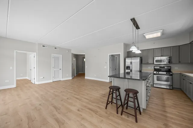 a large kitchen with cabinets wooden floor and stainless steel appliances