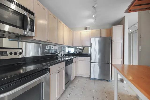 a kitchen with stainless steel appliances granite countertop a refrigerator a stove a sink and a microwave