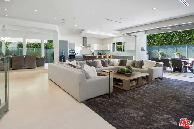 a living room with furniture large windows and wooden floor