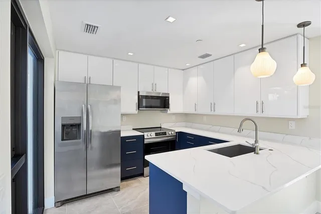 a kitchen with stainless steel appliances a sink a stove a refrigerator and cabinets