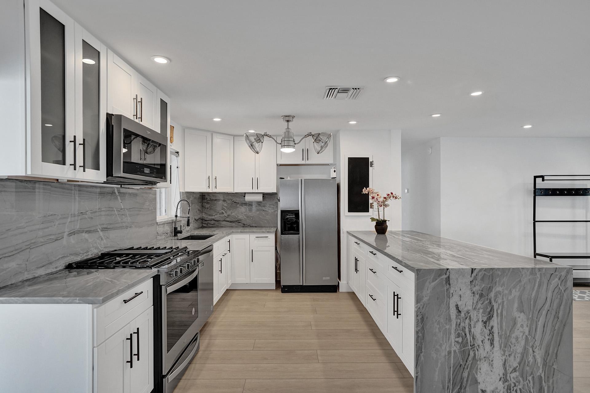 2425 Southeast 6th Street Pompano Beach, FL 33062 - Photo 6 of 18 a large kitchen with stainless steel appliances granite countertop a stove a sink and a refrigerator