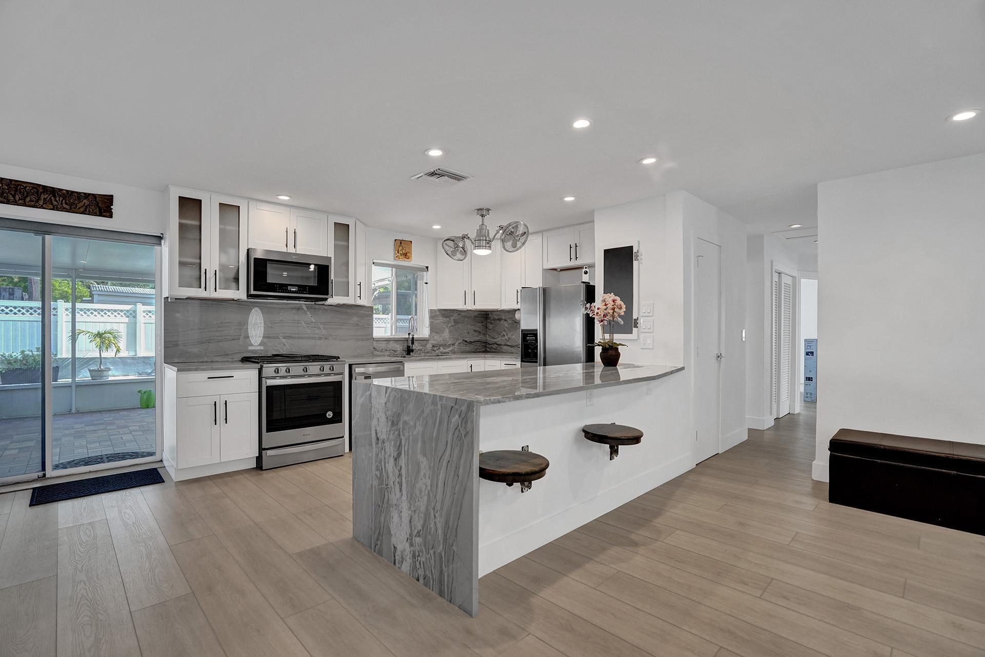 2425 Southeast 6th Street Pompano Beach, FL 33062 - Photo 7 of 18 a large white kitchen with stainless steel appliances granite countertop a stove a sink dishwasher and a oven with wooden floor