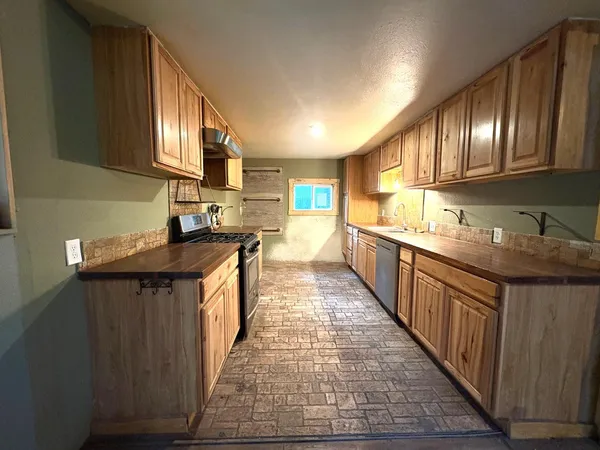 a kitchen with stainless steel appliances granite countertop a stove a sink dishwasher and a refrigerator