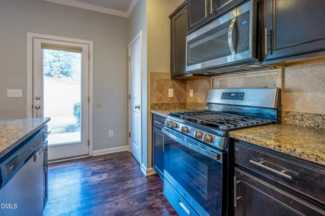a kitchen with granite countertop cabinets stainless steel appliances and a wooden floor