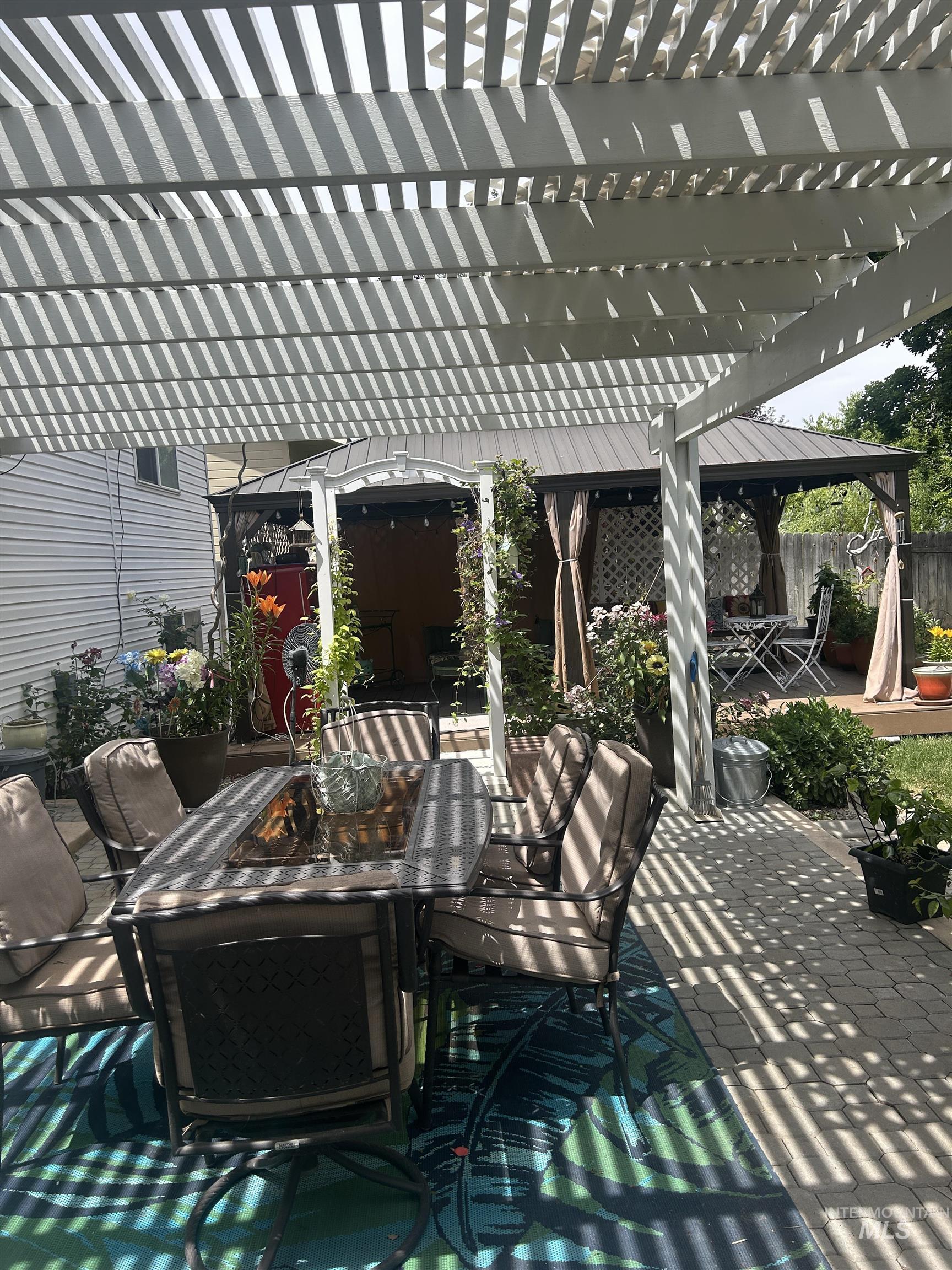 1444 East Doberman Street Meridian, ID 83642 - Photo 24 of 31 Outdoor patio featuring a white slatted pergola, paver stone flooring, and a metal-roofed gazebo