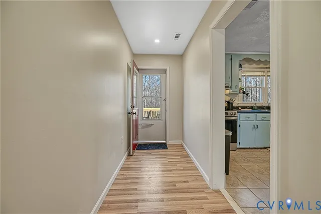 a view of a hallway with wooden floor and a bathroom
