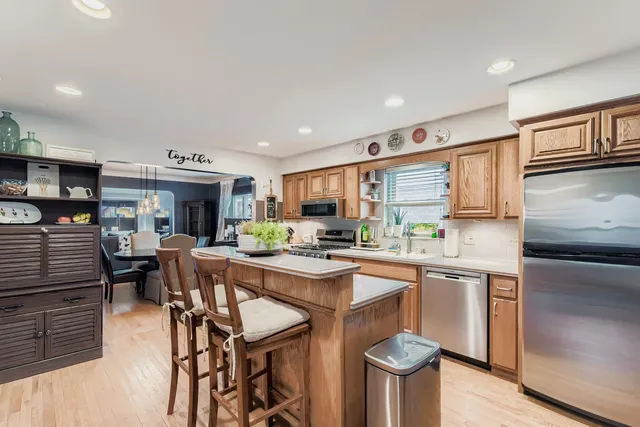 a kitchen with stainless steel appliances granite countertop a stove top oven a sink dishwasher and white cabinets with wooden floor