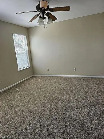 an empty room with a ceiling fan and a window