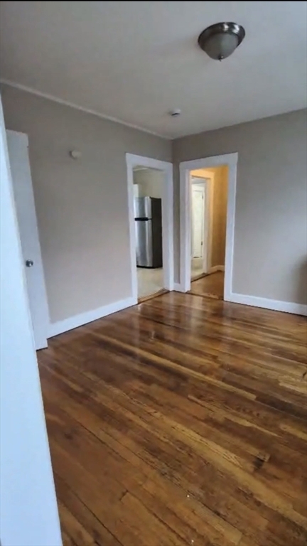 279 Chestnut Street, Unit 2 Lynn, MA 01902 - Photo 12 of 13 a view of an empty room with wooden floor and a window