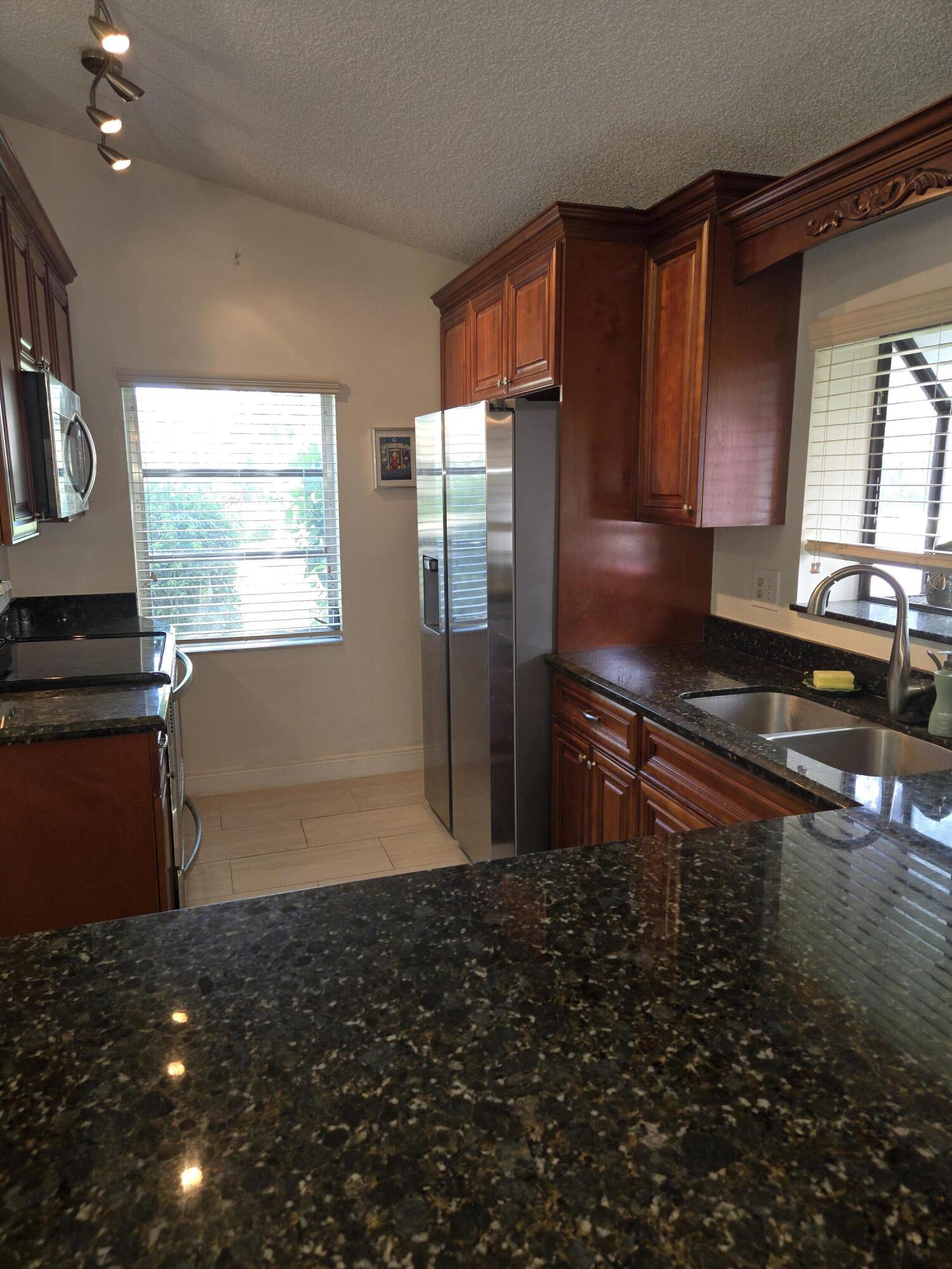 8081 Springtree Road, Unit C Boca Raton, FL 33496 - Photo 11 of 31 a kitchen with granite countertop a refrigerator and a stove