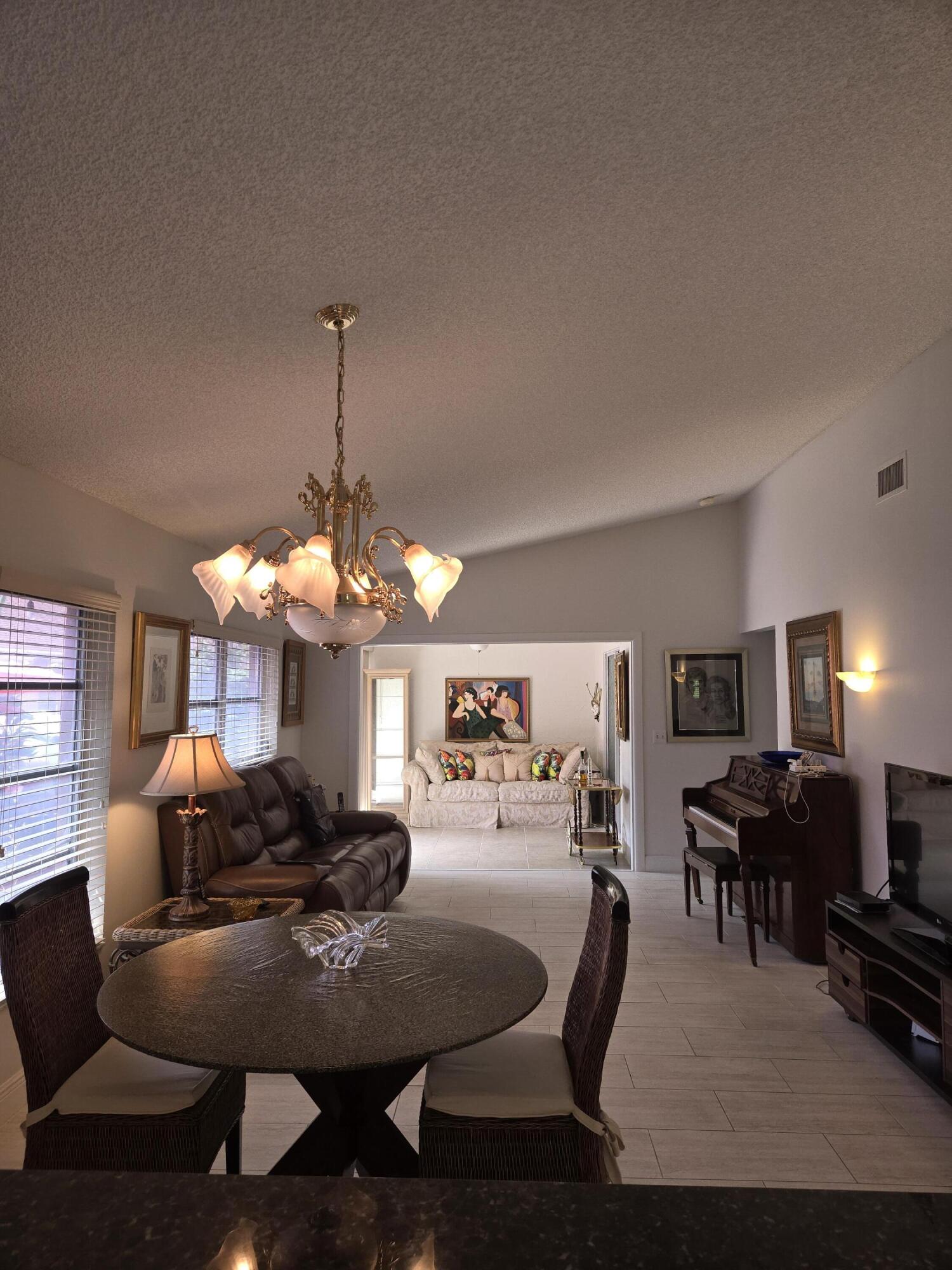 8081 Springtree Road, Unit C Boca Raton, FL 33496 - Photo 3 of 31 a living room with furniture a dining table and a chandelier