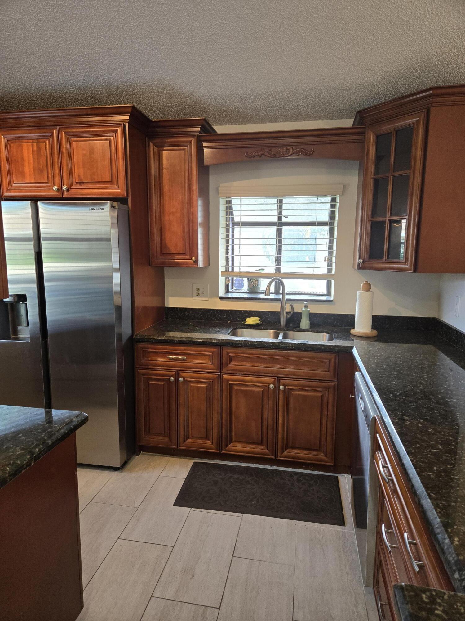 8081 Springtree Road, Unit C Boca Raton, FL 33496 - Photo 7 of 31 a kitchen with granite countertop a refrigerator and a sink