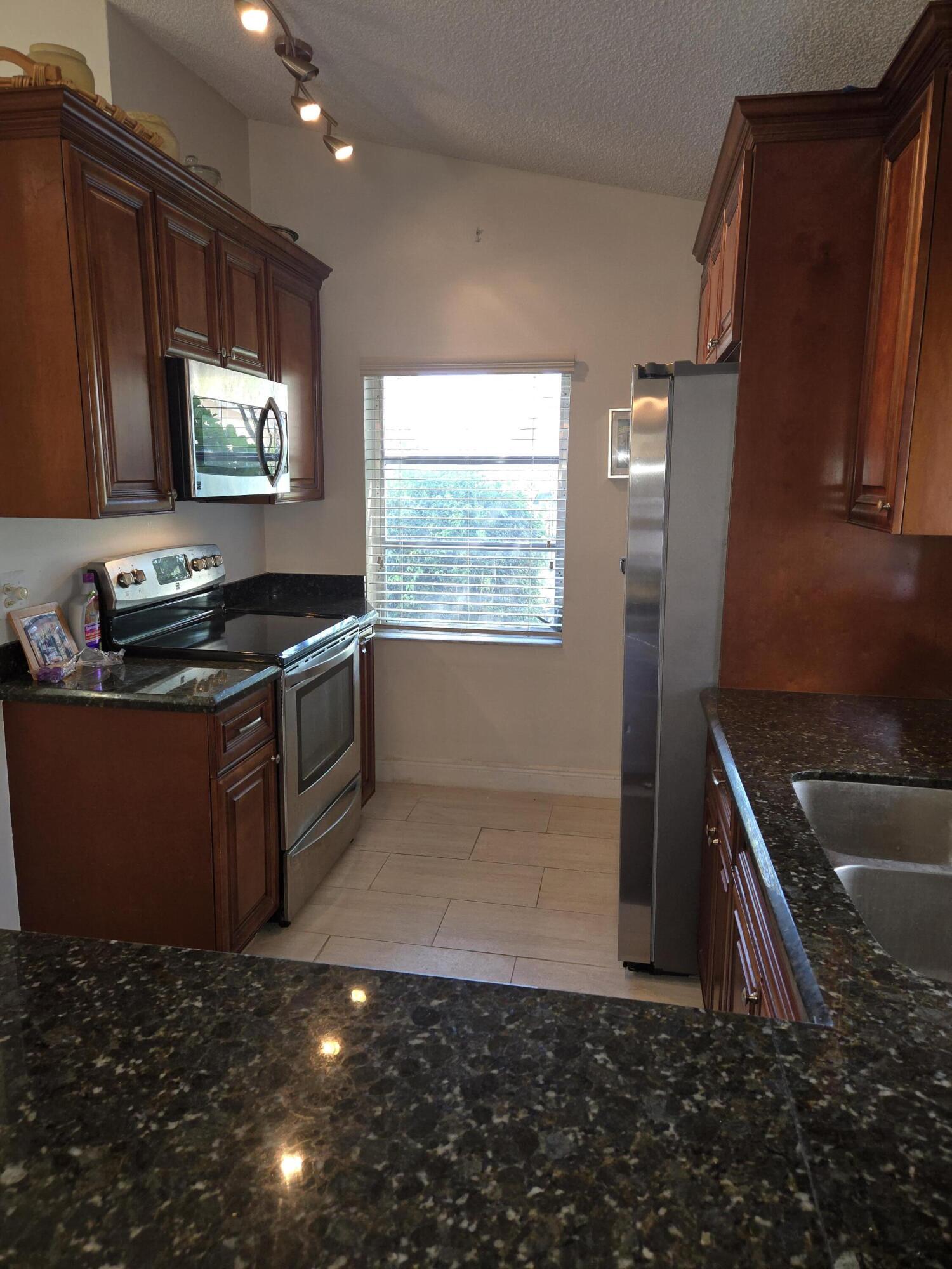 8081 Springtree Road, Unit C Boca Raton, FL 33496 - Photo 9 of 31 a kitchen with granite countertop a stove and a sink
