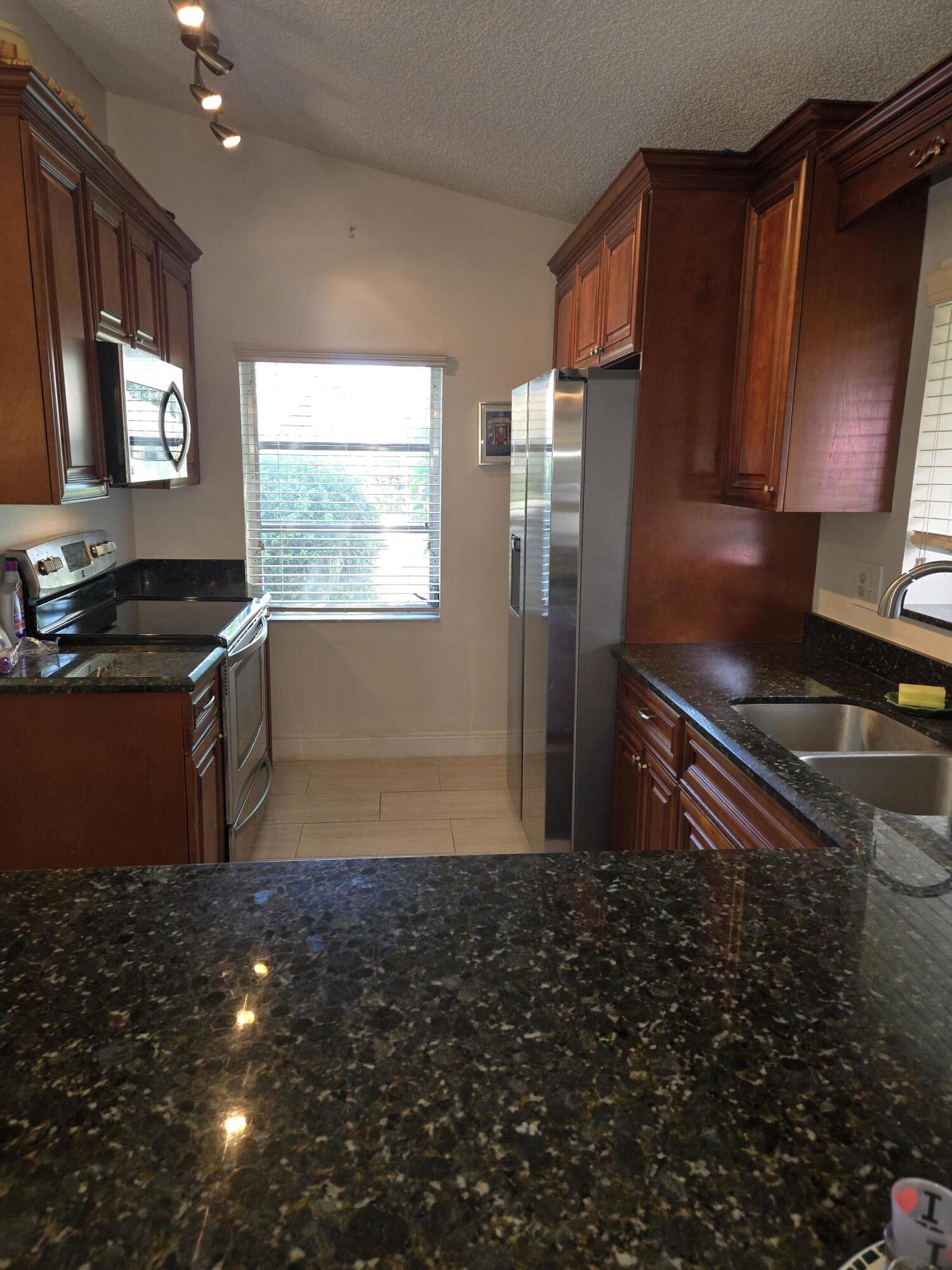 8081 Springtree Road, Unit C Boca Raton, FL 33496 - Photo 10 of 31 a kitchen with granite countertop sink stainless steel appliances and cabinets