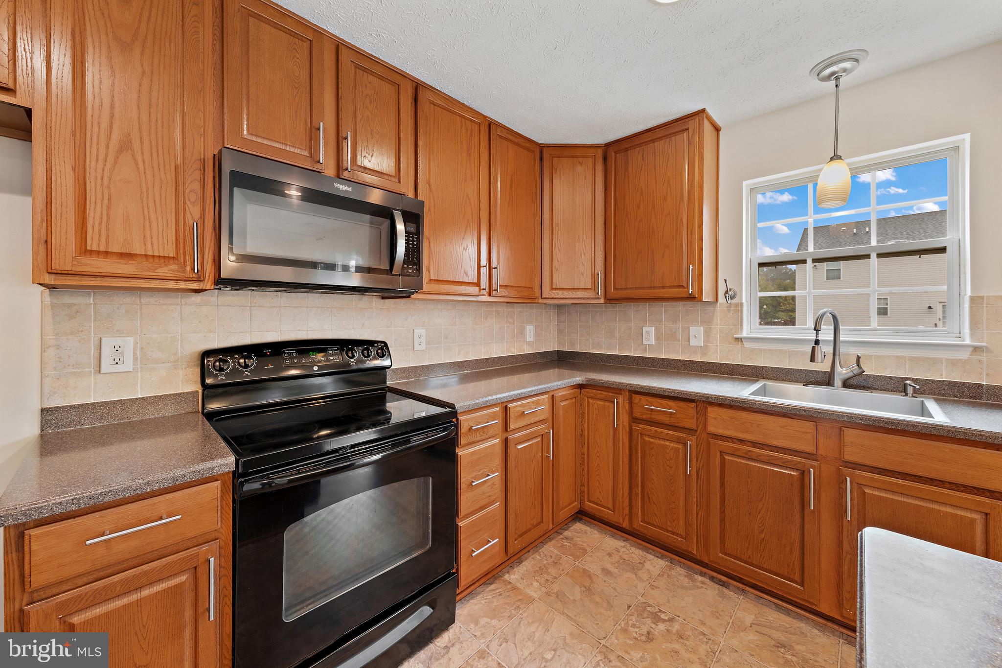 1612 Cattail Commons Way Denton, MD 21629 - Photo 26 of 67 a kitchen with stainless steel appliances granite countertop a sink stove and microwave