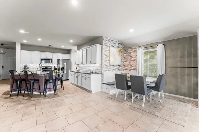 a kitchen with a dining table chairs and white appliances