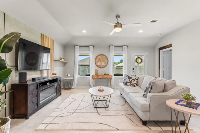 a living room with furniture a flat screen tv and kitchen view