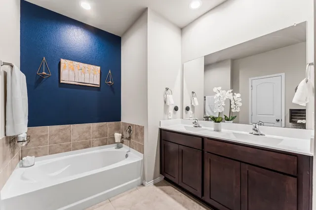 a bathroom with a tub a double vanity sink and mirror