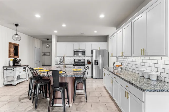 a kitchen with stainless steel appliances kitchen island granite countertop a sink table and chairs