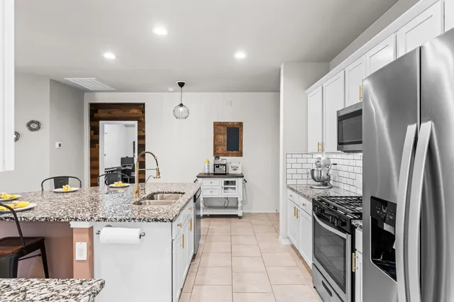 a kitchen with stainless steel appliances granite countertop a sink stove refrigerator and cabinets