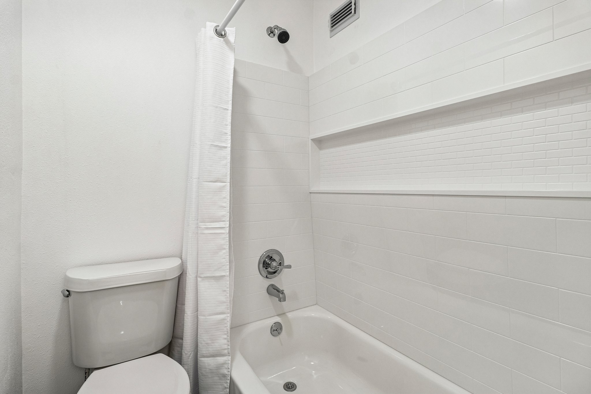 5809 Coventry Lane Austin, TX 78723 - Photo 22 of 35 A pristine bathroom featuring a classic tub and shower combination with stylish white subway tile.