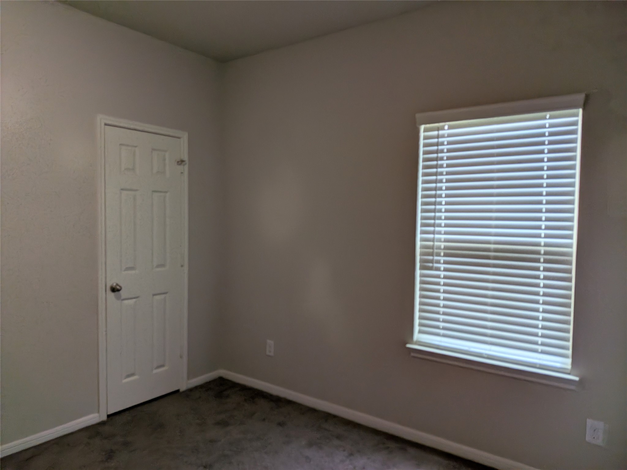 15730 Joe Dimaggio Street Splendora, TX 77372 - Photo 13 of 20 This photo shows a small room with light-colored walls, a window with blinds, and a closed door. It has a simple, clean appearance, ideal for a bedroom or office space.