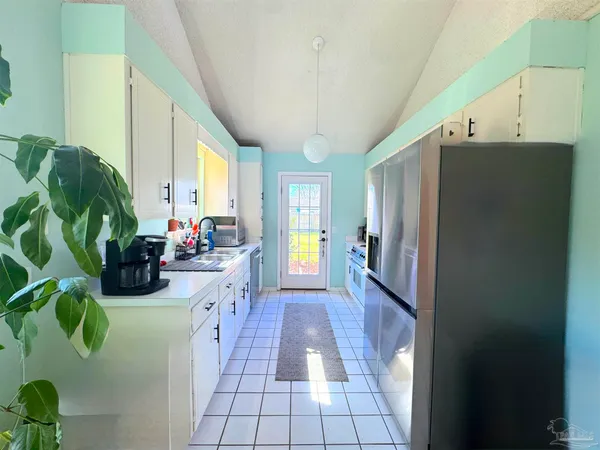 a kitchen with sink a refrigerator and potted plant