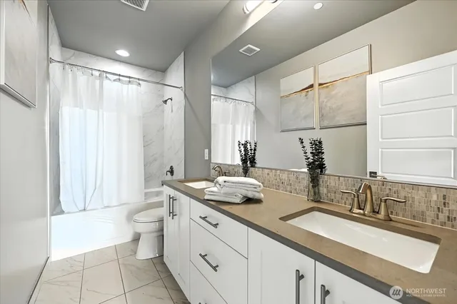 a bathroom with a granite countertop sink a toilet a mirror and shower