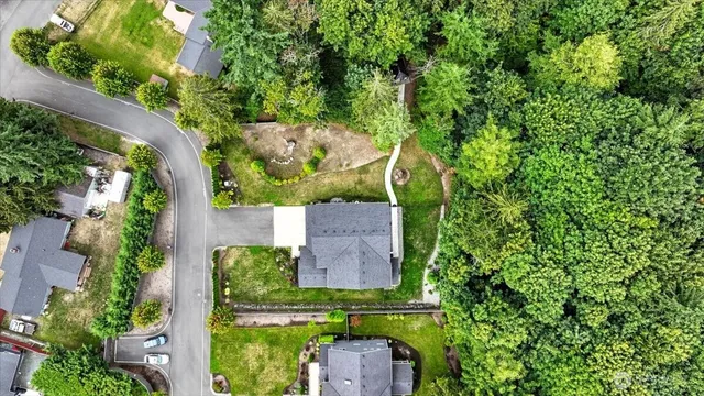 an aerial view of a house with a yard lake and trees all around