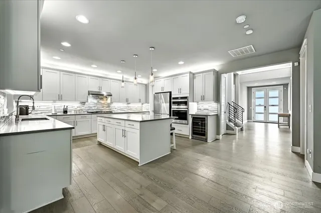a kitchen with stainless steel appliances kitchen island granite countertop wooden floors and white cabinets