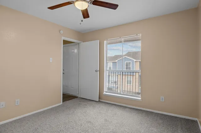an empty room with windows and chandelier fan