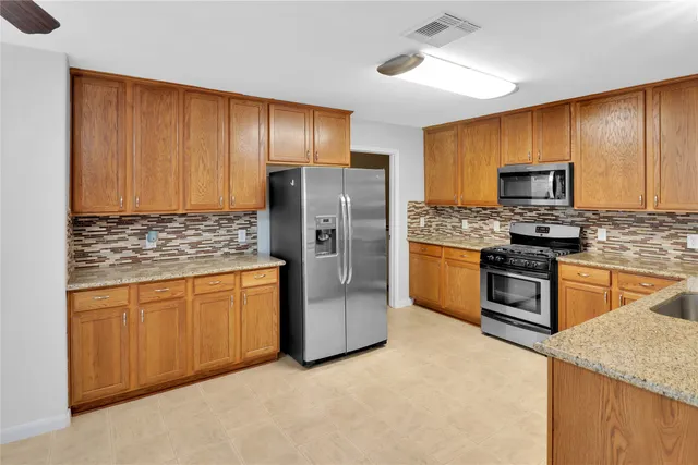 a kitchen with stainless steel appliances granite countertop a stove a sink dishwasher a refrigerator and a oven
