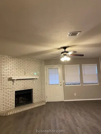 an empty room with windows and fireplace