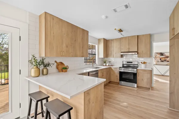 a kitchen with a refrigerator a stove a sink dishwasher and a dining table with wooden floor